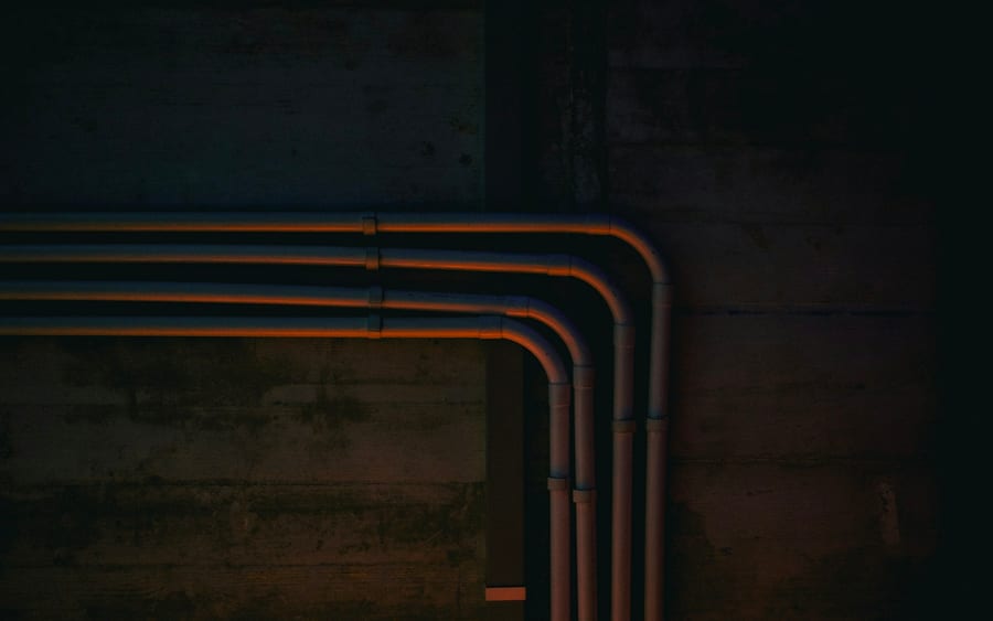 Copper supply pipes bending along a dark basement wall