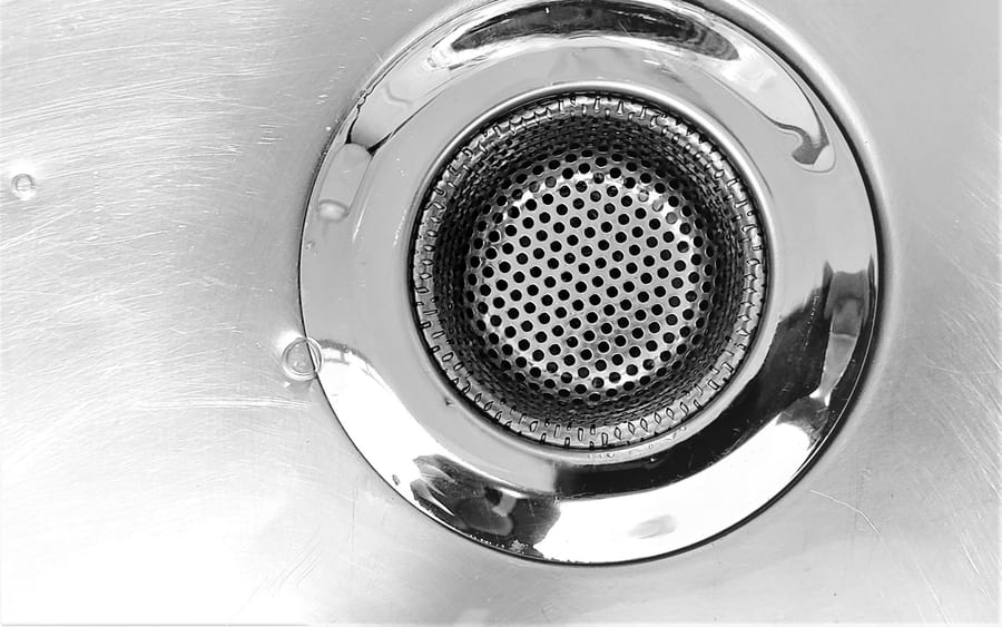 A chrome sink drain with a perforated strainer basket